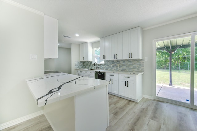 1221 Delores St, Kemah, TX 77565 - kitchen featuring light stone countertops, tasteful backsplash, white cabinets, light wood finished floors, and a peninsula