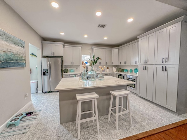 3128 Avenue N, Galveston, TX 77550 - kitchen with appliances with stainless steel finishes, a kitchen breakfast bar, a kitchen island, recessed lighting, and light stone counters