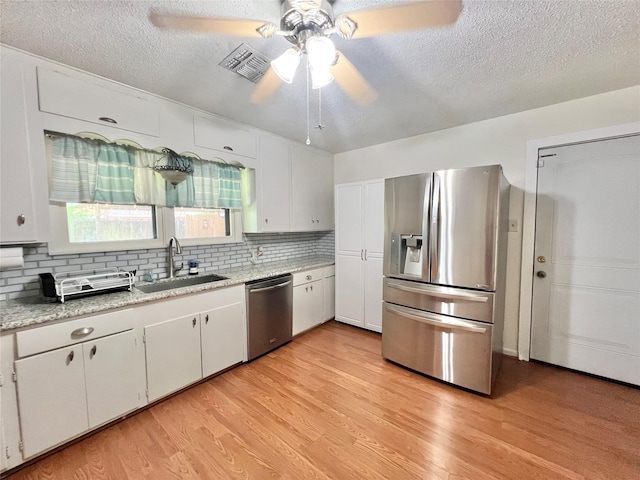 8009 Dellanera Dr, Hitchcock, TX 77563 - kitchen with appliances with stainless steel finishes, a ceiling fan, a textured ceiling, decorative backsplash, and light wood-type flooring