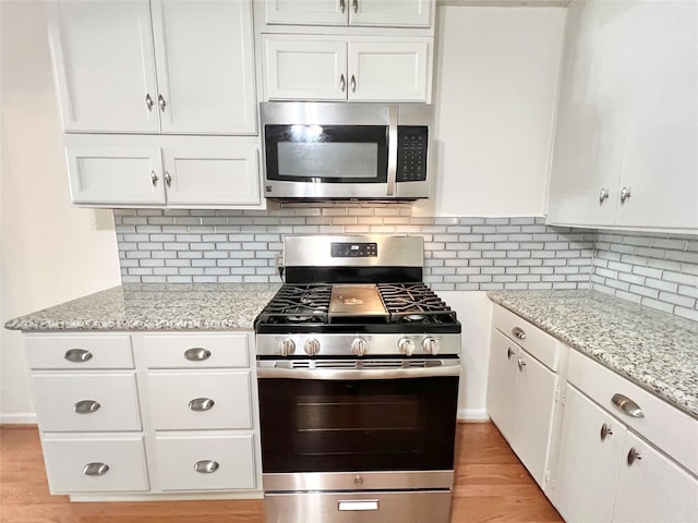 8009 Dellanera Dr, Hitchcock, TX 77563 - kitchen with appliances with stainless steel finishes, white cabinets, light wood-style floors, and light stone countertops
