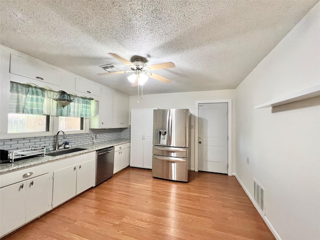 8009 Dellanera Dr, Hitchcock, TX 77563 - kitchen with stainless steel appliances, a textured ceiling, decorative backsplash, a ceiling fan, and light wood-style flooring