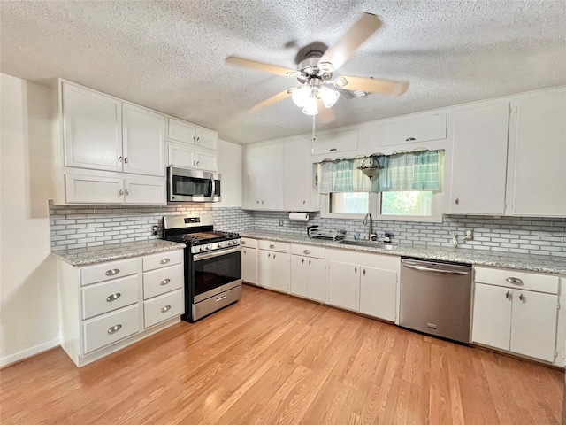 8009 Dellanera Dr, Hitchcock, TX 77563 - kitchen with appliances with stainless steel finishes, a textured ceiling, ceiling fan, white cabinetry, and light wood-type flooring