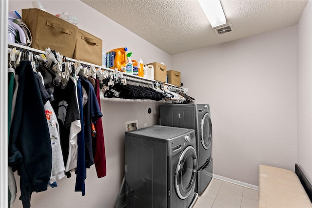 1942 Elkington Cir, Conroe, TX 77304 - laundry room featuring washer and clothes dryer, a textured ceiling, and light tile patterned flooring