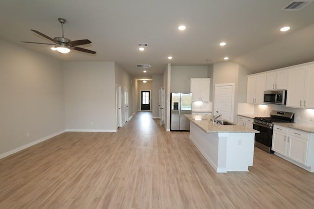 4989 Perennial Ln, La Marque, TX 77568 - kitchen with stainless steel appliances, open floor plan, light wood finished floors, a center island with sink, and tasteful backsplash