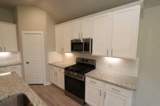 4989 Perennial Ln, La Marque, TX 77568 - kitchen featuring stainless steel appliances, light wood-style flooring, white cabinets, backsplash, and light stone counters