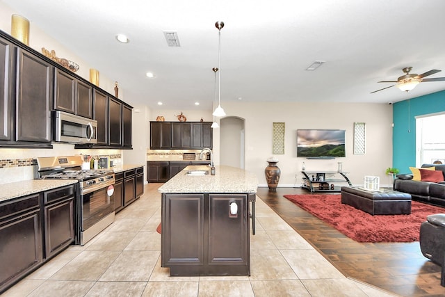 9430 Jayci Hills Ln, Cypress, TX 77433 - kitchen with stainless steel appliances, open floor plan, arched walkways, light stone countertops, and ceiling fan