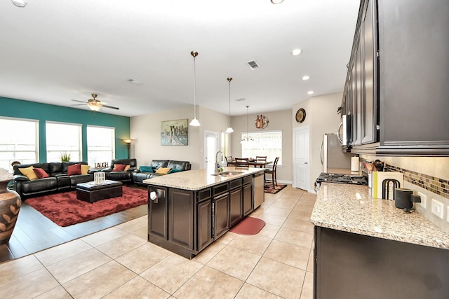 9430 Jayci Hills Ln, Cypress, TX 77433 - kitchen with backsplash, a ceiling fan, dark brown cabinetry, an island with sink, and light stone counters