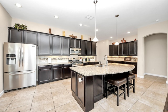 9430 Jayci Hills Ln, Cypress, TX 77433 - kitchen with appliances with stainless steel finishes, light stone countertops, backsplash, light tile patterned flooring, and a kitchen island with sink
