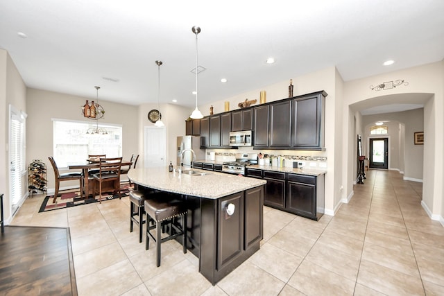9430 Jayci Hills Ln, Cypress, TX 77433 - kitchen featuring stainless steel appliances, arched walkways, a kitchen breakfast bar, a kitchen island with sink, and pendant lighting