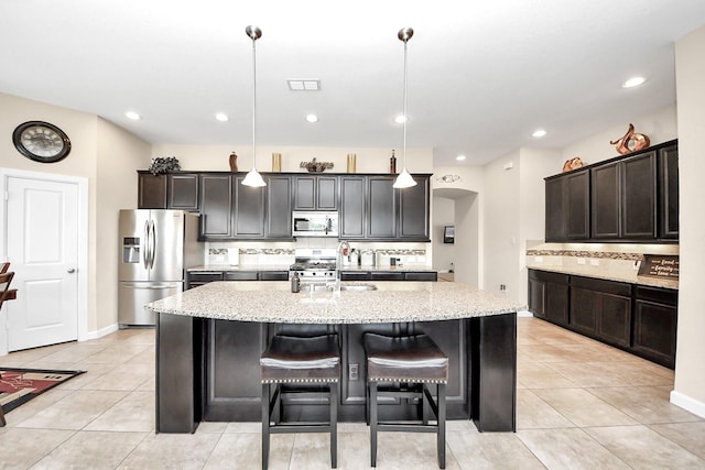 9430 Jayci Hills Ln, Cypress, TX 77433 - kitchen featuring appliances with stainless steel finishes, tasteful backsplash, light stone countertops, a center island with sink, and recessed lighting