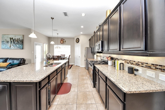 9430 Jayci Hills Ln, Cypress, TX 77433 - kitchen featuring appliances with stainless steel finishes, a center island with sink, backsplash, light stone countertops, and recessed lighting