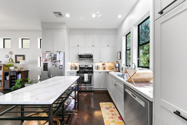 1807 Dart St, Houston, TX 77007 - kitchen featuring appliances with stainless steel finishes, dark wood-style floors, decorative backsplash, recessed lighting, and light stone countertops