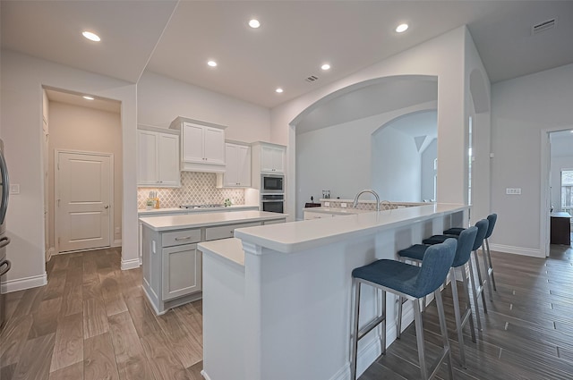 2430 Sunflower Cove Ln, Brookshire, TX 77423 - kitchen featuring stainless steel appliances, a kitchen island with sink, a breakfast bar, dark wood finished floors, and light countertops