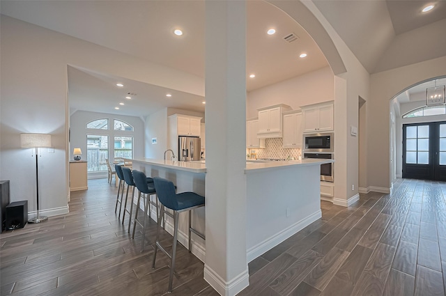 2430 Sunflower Cove Ln, Brookshire, TX 77423 - kitchen with appliances with stainless steel finishes, dark wood-type flooring, vaulted ceiling, arched walkways, and light countertops