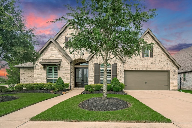 2430 Sunflower Cove Ln, Brookshire, TX 77423 - french country home with french doors, driveway, a front lawn, brick siding, and an attached garage