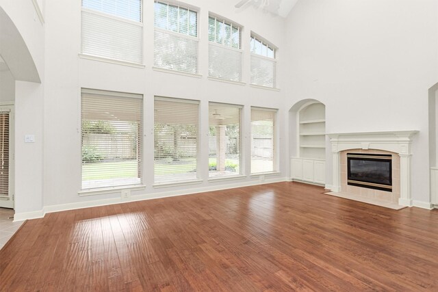 14015 Halprin Creek Dr, Cypress, TX 77429 - unfurnished living room featuring a towering ceiling, a heating unit, a tile fireplace, healthy amount of natural light, and built in features