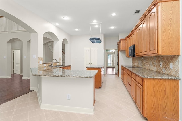 14015 Halprin Creek Dr, Cypress, TX 77429 - kitchen with black appliances, backsplash, light stone countertops, a peninsula, and recessed lighting