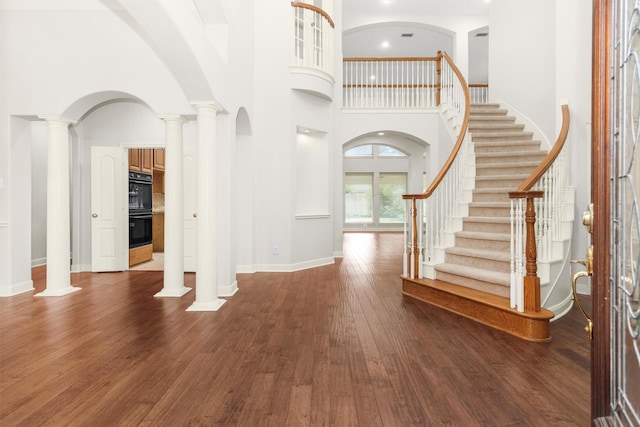 14015 Halprin Creek Dr, Cypress, TX 77429 - entrance foyer with a towering ceiling, dark wood-style flooring, ornate columns, stairs, and arched walkways