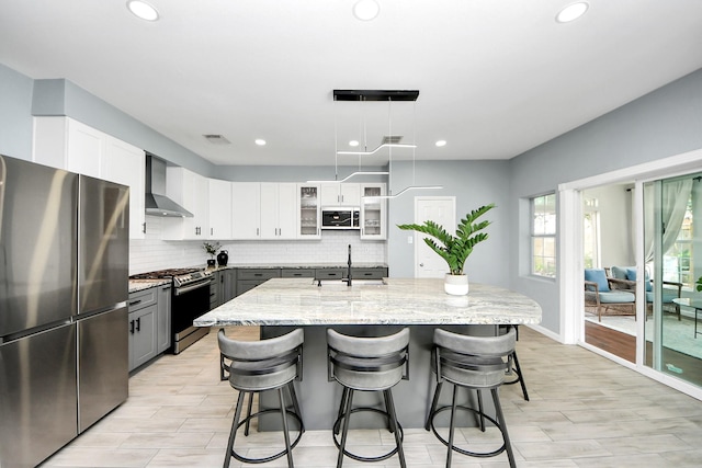 7619 Park Sage Ln, Cypress, TX 77433 - kitchen featuring stainless steel appliances, wall chimney range hood, recessed lighting, light stone countertops, and decorative backsplash