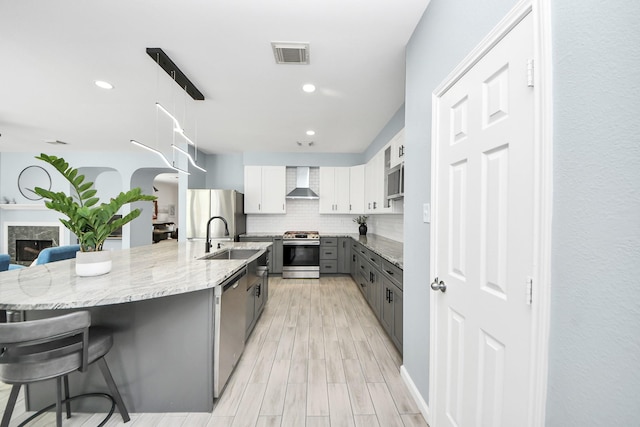 7619 Park Sage Ln, Cypress, TX 77433 - kitchen featuring stainless steel appliances, gray cabinets, wall chimney range hood, a breakfast bar, and tasteful backsplash