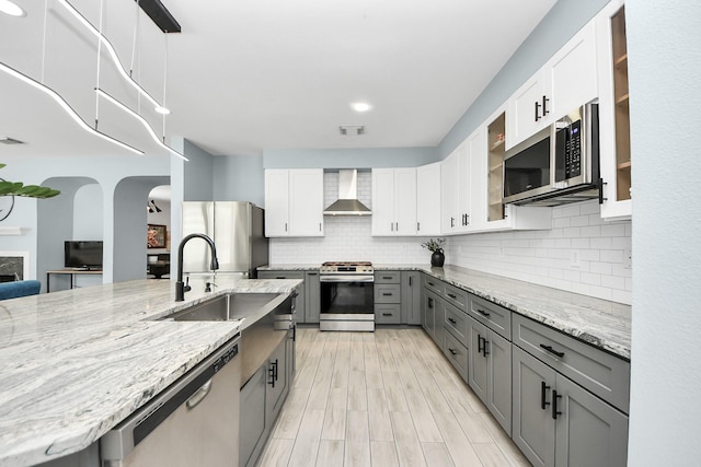 7619 Park Sage Ln, Cypress, TX 77433 - kitchen with stainless steel appliances, wall chimney exhaust hood, gray cabinetry, and light stone counters