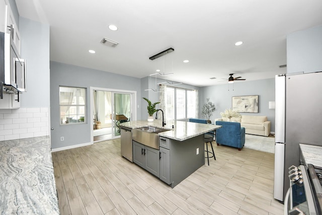 7619 Park Sage Ln, Cypress, TX 77433 - kitchen with open floor plan, appliances with stainless steel finishes, a ceiling fan, light stone countertops, and a breakfast bar