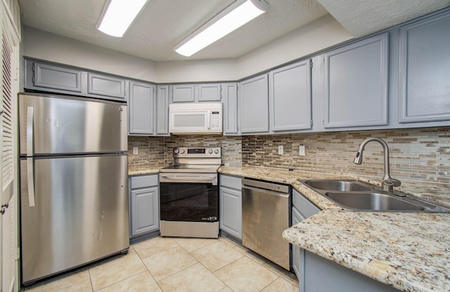 10555 Turtlewood Ct Unit 2802, Houston, TX 77072 - kitchen with stainless steel appliances, gray cabinetry, light tile patterned floors, decorative backsplash, and light stone counters
