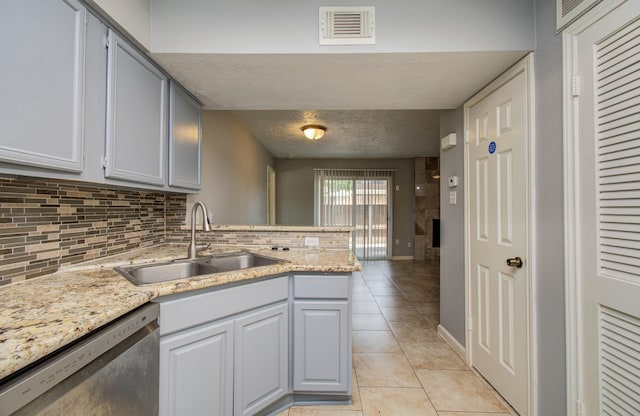10555 Turtlewood Ct Unit 2802, Houston, TX 77072 - kitchen featuring stainless steel dishwasher, backsplash, a peninsula, light tile patterned floors, and a textured ceiling