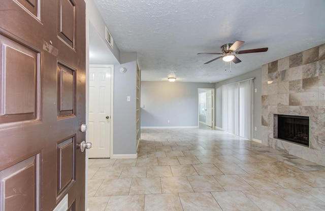 10555 Turtlewood Ct Unit 2802, Houston, TX 77072 - unfurnished living room featuring ceiling fan, a tiled fireplace, a textured ceiling, and light tile patterned floors