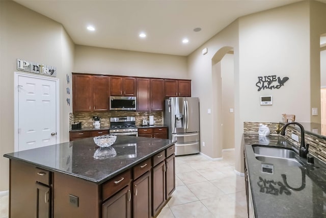 4507 Cinco Forest Trl, Katy, TX 77494 - kitchen with appliances with stainless steel finishes, decorative backsplash, arched walkways, dark stone countertops, and light tile patterned floors