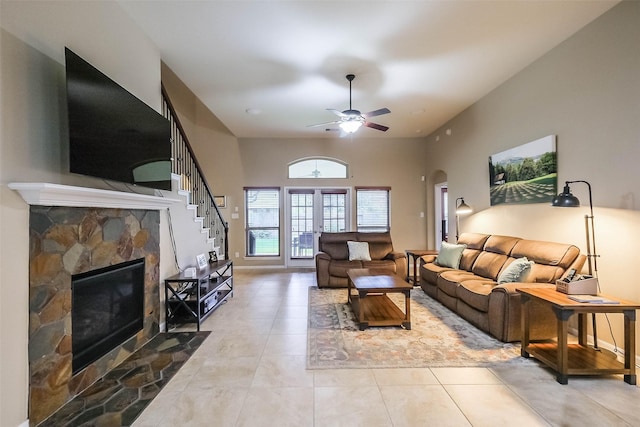 4507 Cinco Forest Trl, Katy, TX 77494 - living area featuring a stone fireplace, tile patterned flooring, stairway, a ceiling fan, and a towering ceiling