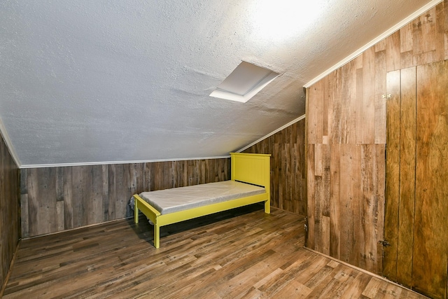 325 Carolcrest Ln Unit 3, Livingston, TX 77351 - unfurnished bedroom featuring a textured ceiling, vaulted ceiling, wood finished floors, and wood walls