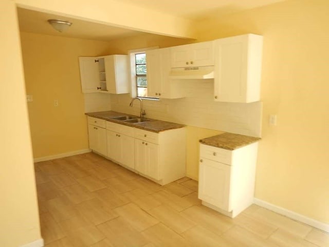 7121 Conley St, Houston, TX 77021 - kitchen with under cabinet range hood, backsplash, white cabinets, and light wood-style flooring