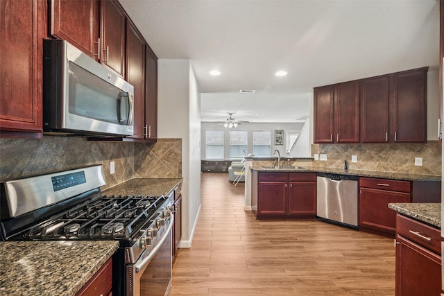 16743 Fallen Timbers Dr, Conroe, TX 77385 - kitchen with appliances with stainless steel finishes, light wood finished floors, dark stone counters, recessed lighting, and ceiling fan