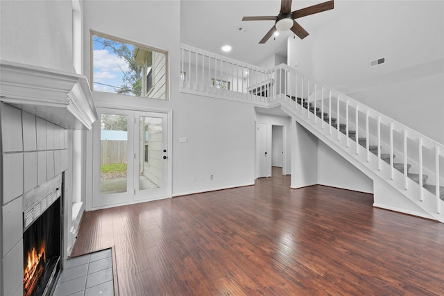 12319 Hamsfield Ct, Tomball, TX 77377 - unfurnished living room with a towering ceiling, a lit fireplace, ceiling fan, stairs, and wood finished floors