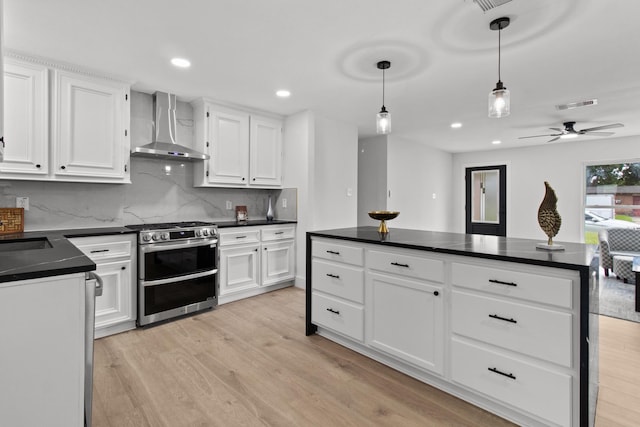 806 Lyngrove Dr, Houston, TX 77038 - kitchen featuring range with two ovens, wall chimney range hood, dark countertops, light wood finished floors, and recessed lighting