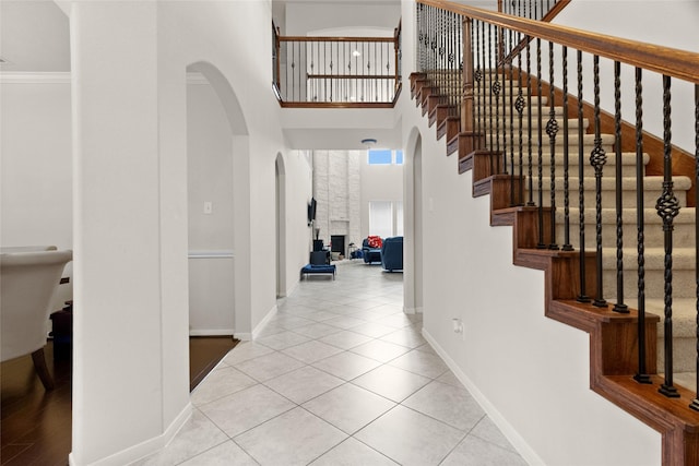 3922 Crestwind Ln, Richmond, TX 77407 - foyer featuring arched walkways, a high ceiling, stairs, tile patterned flooring, and crown molding