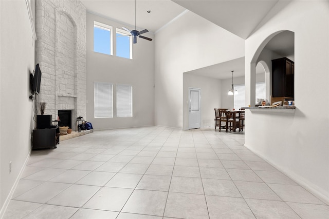 3922 Crestwind Ln, Richmond, TX 77407 - living room with a fireplace, a ceiling fan, a towering ceiling, and light tile patterned floors