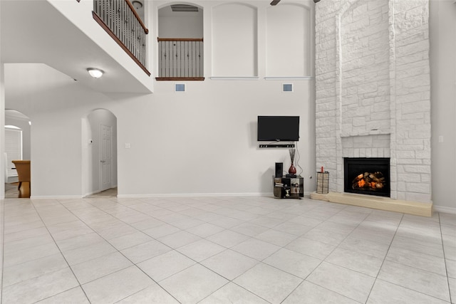 3922 Crestwind Ln, Richmond, TX 77407 - unfurnished living room featuring a high ceiling, light tile patterned floors, a fireplace, and arched walkways