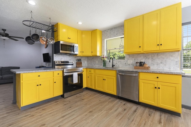 418 E Cedar Bayou Lynchburg Rd, Baytown, TX 77521 - kitchen with stainless steel appliances, a peninsula, light wood-style flooring, healthy amount of natural light, and a textured ceiling
