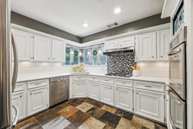 14615 Sunny Grove Dr, Houston, TX 77070 - kitchen featuring stainless steel appliances, white cabinetry, light countertops, under cabinet range hood, and a textured ceiling