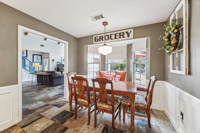 14615 Sunny Grove Dr, Houston, TX 77070 - dining room with stone tile floors, wainscoting, and a decorative wall