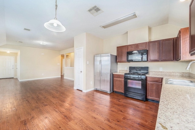 12006 Gregory Crossing Way, Houston, TX 77067 - kitchen with black appliances, dark wood finished floors, pendant lighting, lofted ceiling, and open floor plan