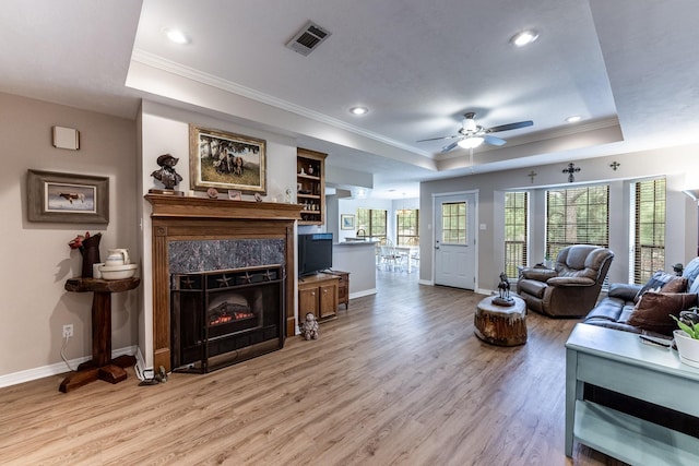 1608 Durham Dr, Huntsville, TX 77340 - living area featuring a tray ceiling, crown molding, light wood-style floors, ceiling fan, and a fireplace