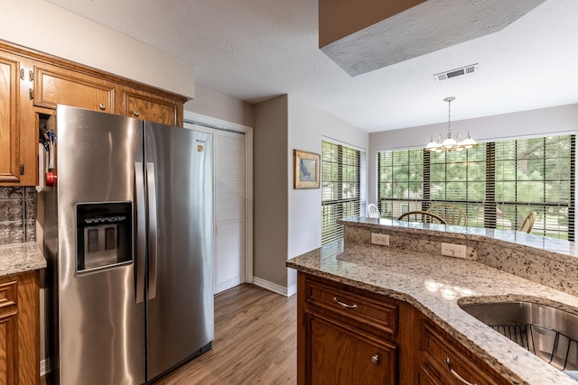 1608 Durham Dr, Huntsville, TX 77340 - kitchen with stainless steel fridge, light wood-type flooring, a chandelier, brown cabinets, and hanging light fixtures