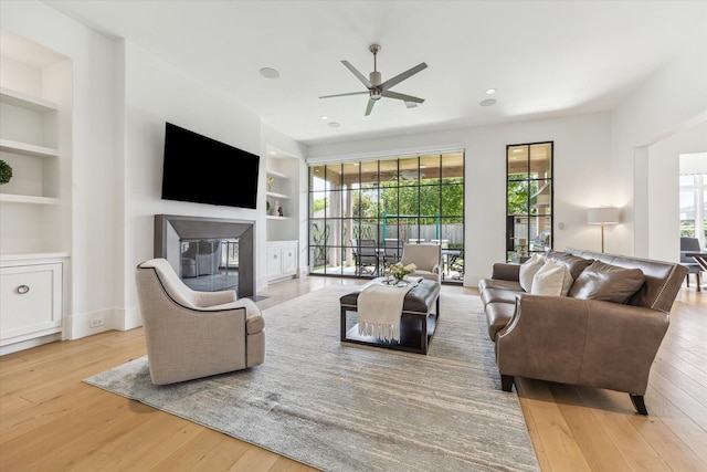 6626 Westchester Ave, West University Place, TX 77005 - living room with built in shelves, a ceiling fan, hardwood / wood-style floors, and a glass covered fireplace