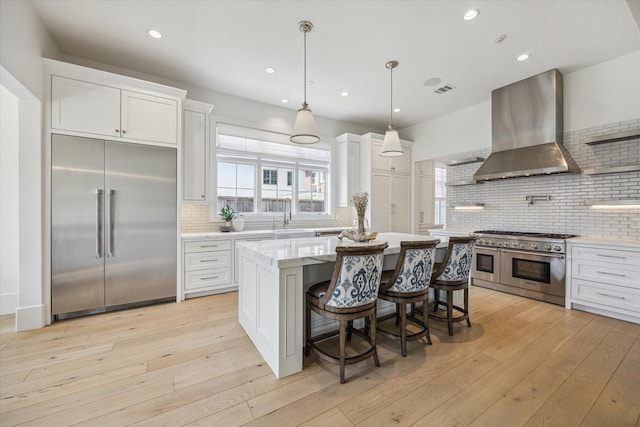 6626 Westchester Ave, West University Place, TX 77005 - kitchen featuring high end appliances, wall chimney range hood, tasteful backsplash, white cabinets, and recessed lighting