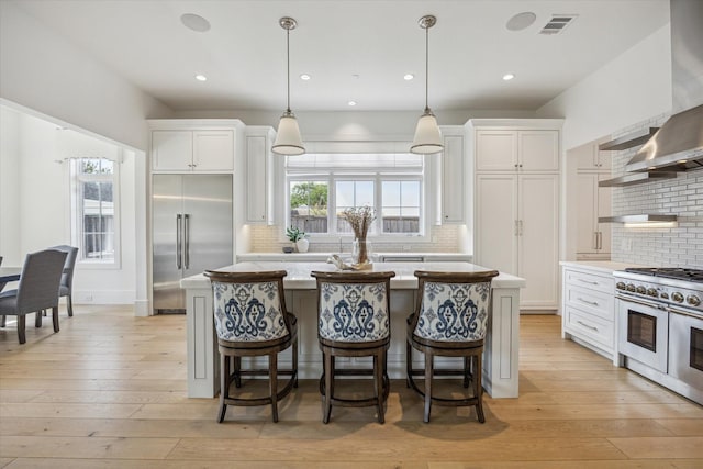 6626 Westchester Ave, West University Place, TX 77005 - kitchen with high end appliances, wall chimney exhaust hood, a center island, tasteful backsplash, and recessed lighting