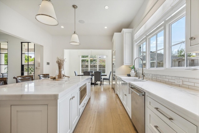 6626 Westchester Ave, West University Place, TX 77005 - kitchen featuring stainless steel appliances, white cabinetry, a kitchen island, light stone countertops, and recessed lighting