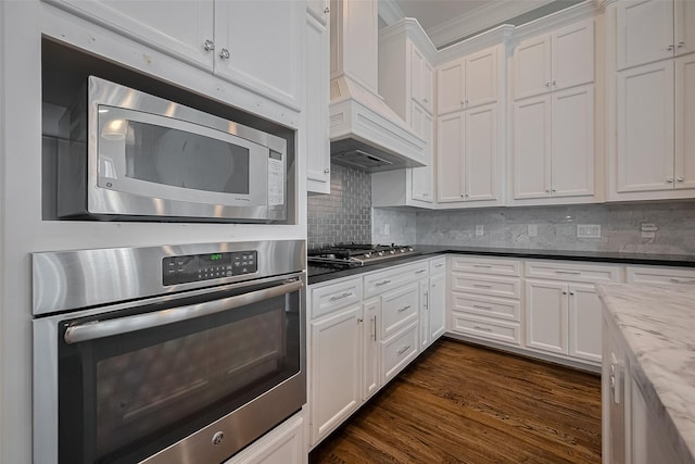 2106 Bidwell Dr, Houston, TX 77018 - kitchen with stainless steel appliances, premium range hood, ornamental molding, white cabinetry, and backsplash